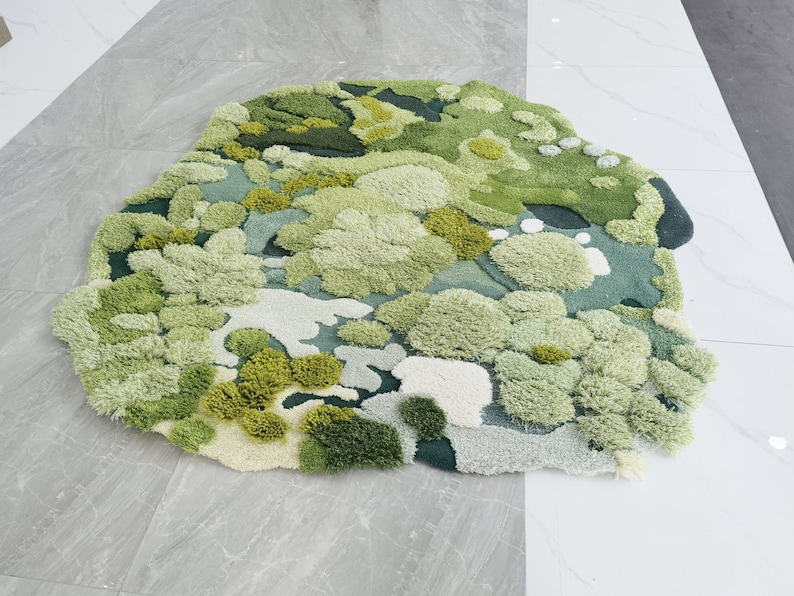 May include: A green and white rug with a textured, fluffy surface. The rug is designed to look like a field of grass with different shades of green and white.