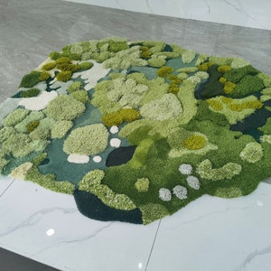 May include: A green and white abstract rug with a textured, fluffy surface. The rug is shaped like a cloud and has a variety of different shades of green.