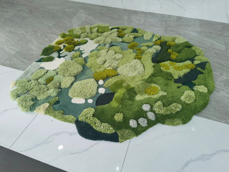May include: A green and white abstract rug with a textured, fluffy surface. The rug is shaped like a cloud and has a variety of different shades of green.