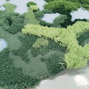 May include: Close-up of a green and blue textured rug with a fluffy, shaggy surface. The rug has a unique abstract design with different shades of green and blue.