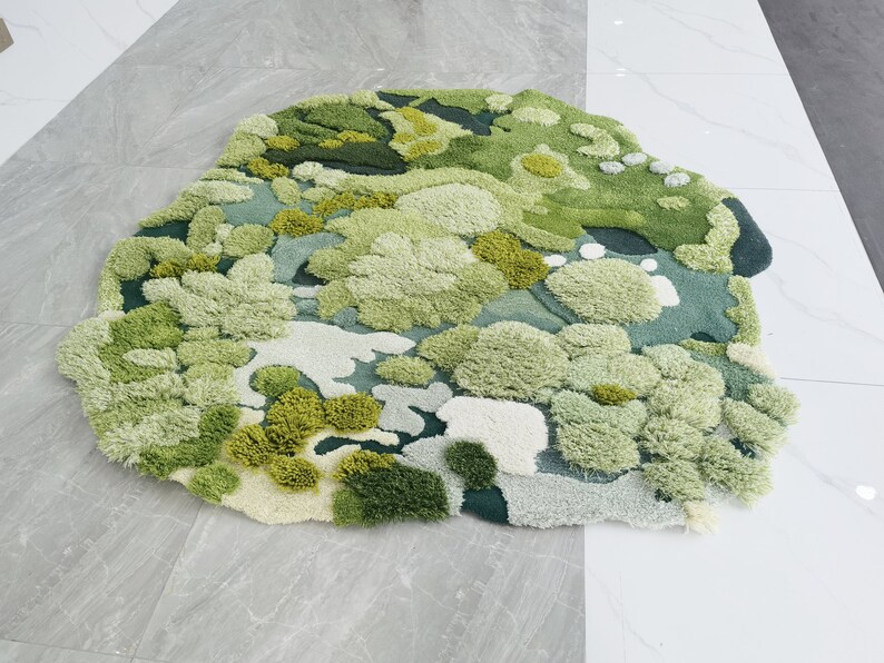 May include: A green and white rug with a textured, fluffy surface. The rug is designed to look like a field of grass with different shades of green and white.