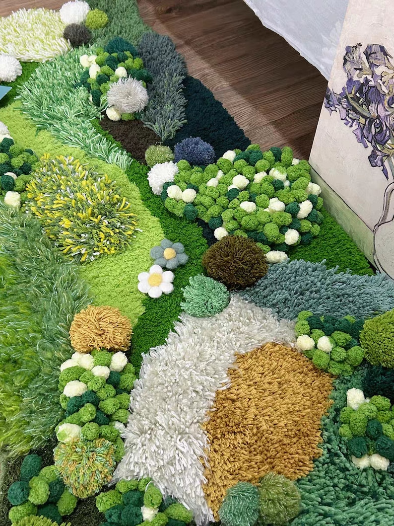 May include: A green, white, and yellow rug with a textured, fluffy surface. The rug features a variety of shapes and textures, including pom-poms, grass, and flowers.