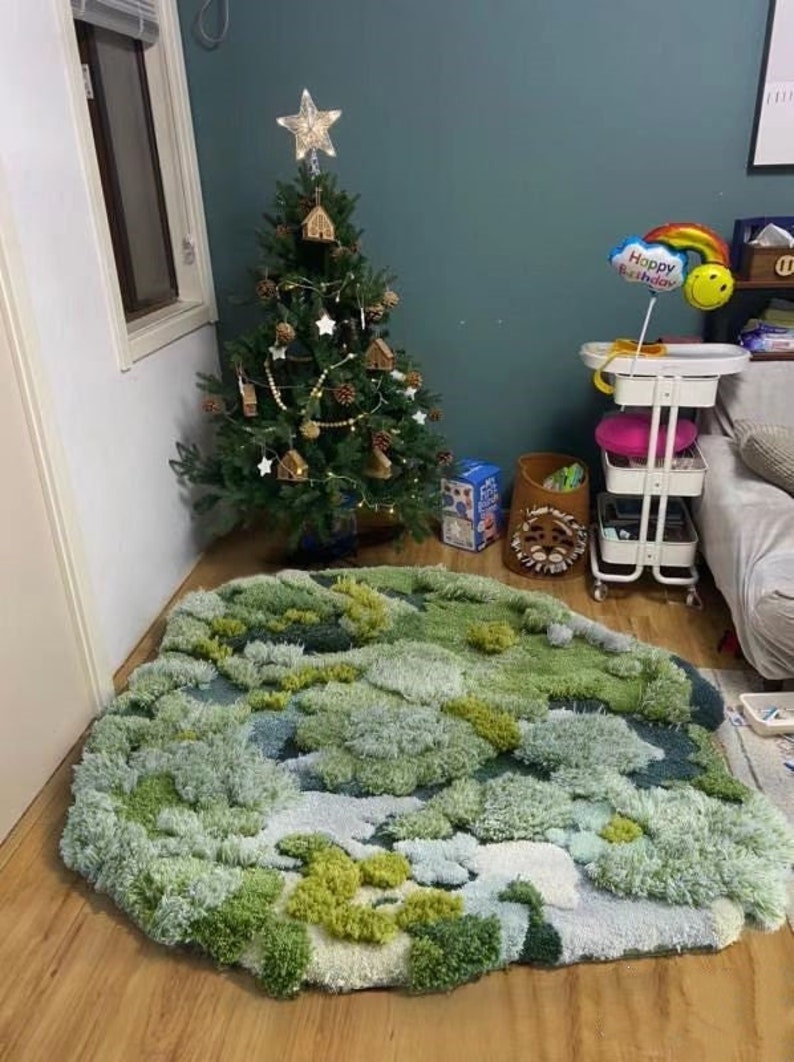 May include: A green and blue shag rug with a unique, abstract design. The rug is in a room with a decorated Christmas tree and a white rolling cart.