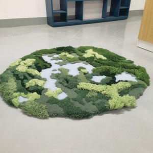 May include: A green and white rug with a textured, landscape design. The rug is made of soft, fluffy material and resembles a miniature forest.