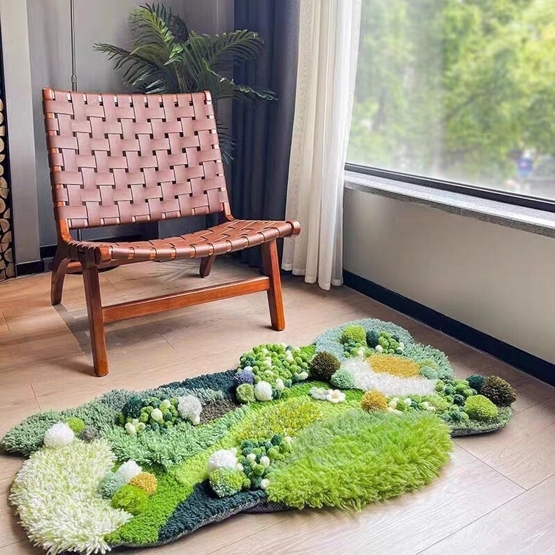 May include: A green, white, and brown rug with a textured, fluffy surface. The rug is shaped like a cloud and has a variety of different textures and patterns. A brown leather chair sits in front of the rug.