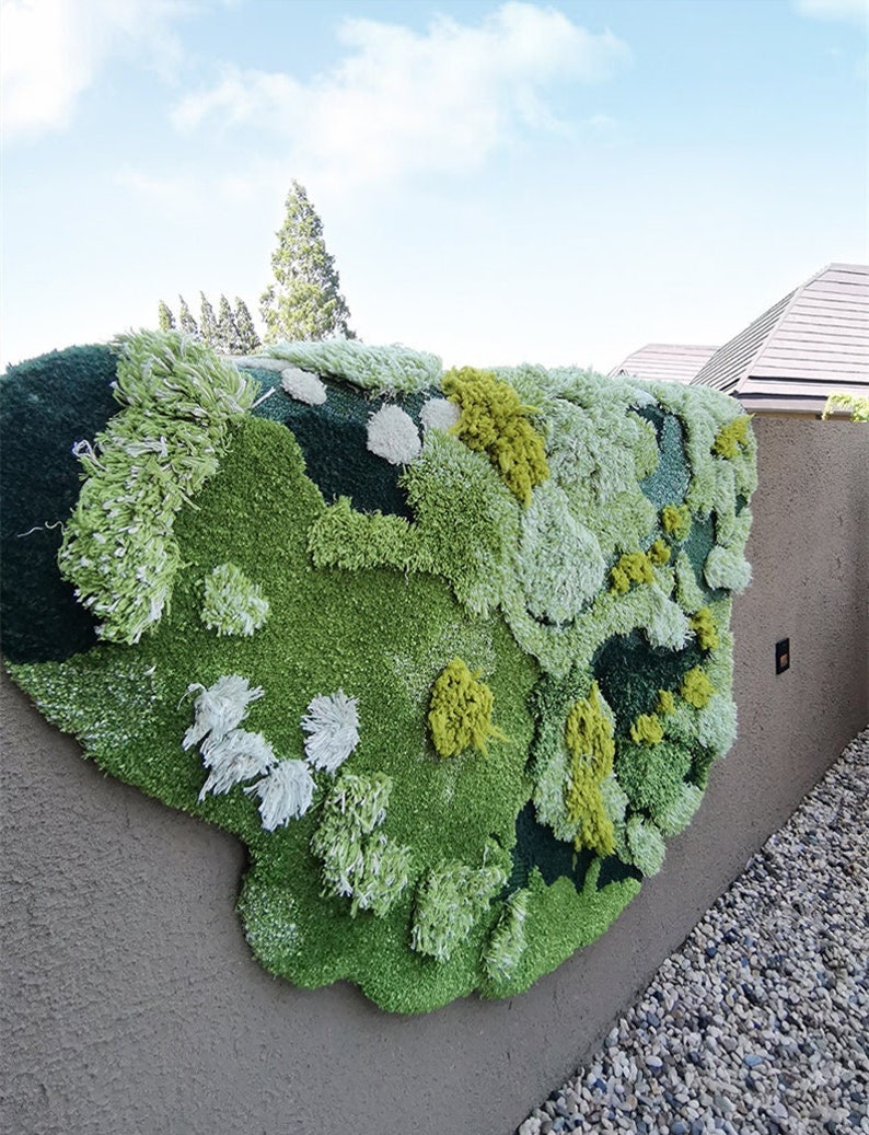 May include: A large, green, white, and yellow wall hanging made of fluffy yarn. The wall hanging is shaped like a cloud and has a textured, organic look.