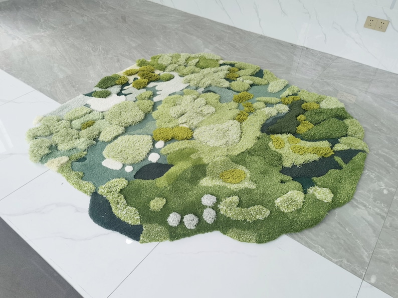 May include: A green and white abstract rug with a textured, fluffy surface. The rug is shaped like a cloud and has a variety of different shades of green.