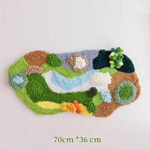 May include: A green, brown, blue, and white plush rug with a variety of textures and shapes. The rug is shaped like a landscape with hills, a river, and trees. It measures 70 cm by 36 cm.