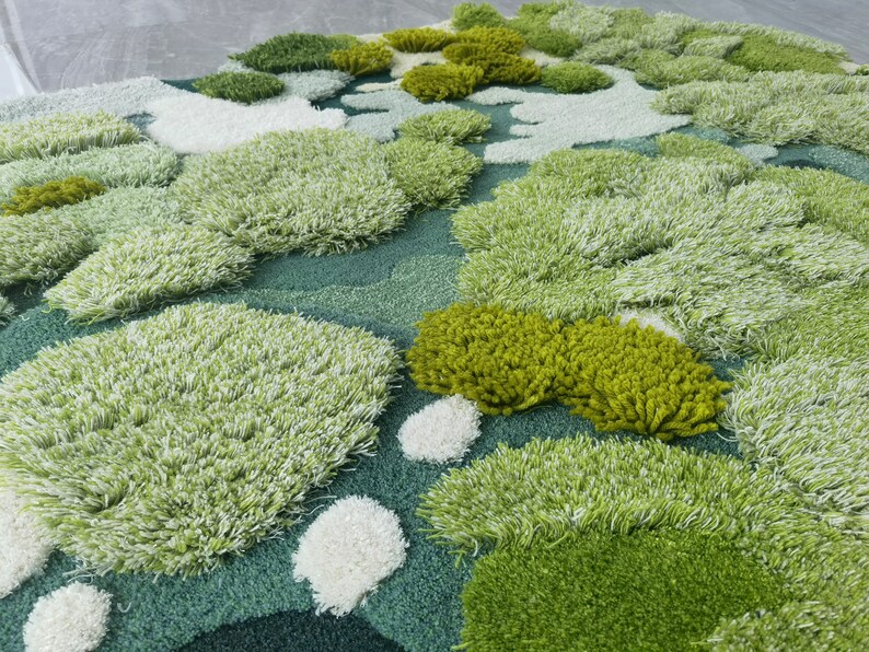 May include: A close-up of a green and white textured rug with a variety of shapes and sizes. The rug is made of soft, fluffy fibers and has a unique, organic look.
