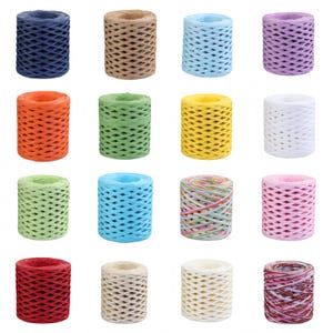 Puede incluir: Dieciséis bobinas cilíndricas de cinta de rafia de papel dispuestas en una cuadrícula de cuatro por cuatro. Las bobinas presentan una variedad de colores sólidos que incluyen azul marino, tostado, azul claro, lavanda, naranja, verde, amarillo, blanco, lima, cian, rosa y rojo.