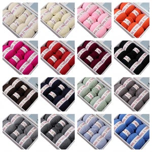 May include: A selection of yarn skeins in diverse colours, presented in white boxes. Each box holds multiple balls of yarn, labelled "THREE WOOL THREAD". Colours include white, pink, orange, red, black, brown, navy, green, grey, and blue.