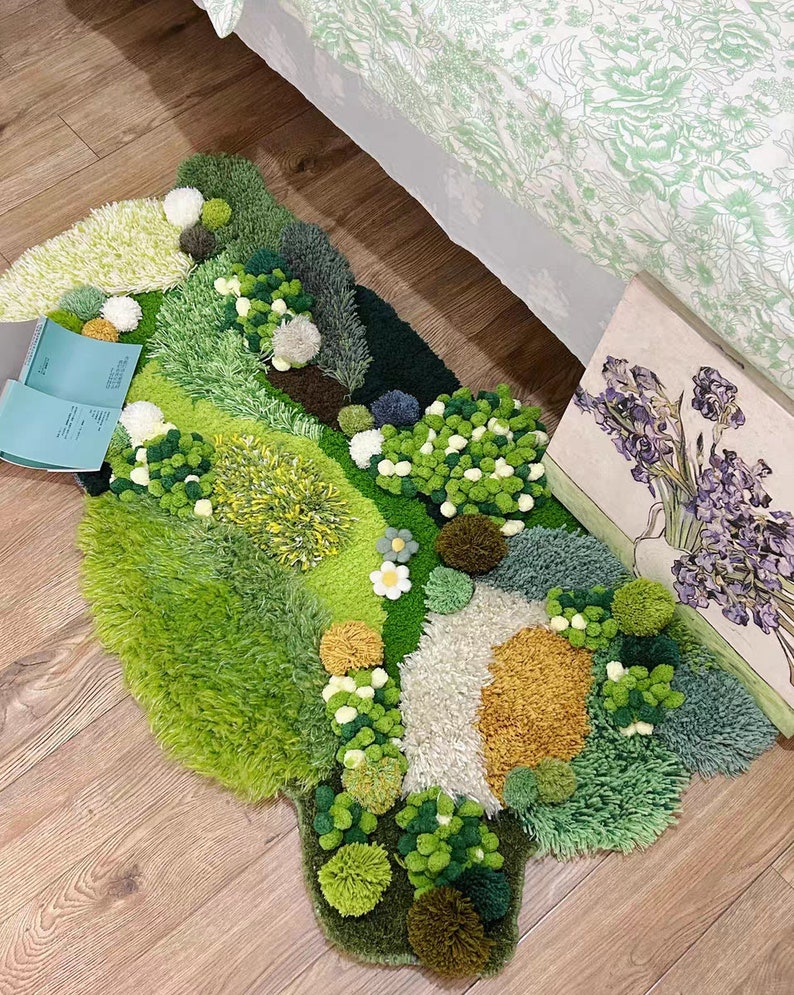May include: A green, brown, and white rug with a textured, fluffy surface. The rug is shaped like a landscape with different colored patches of grass and flowers. The rug is made of yarn and has a 3D effect.