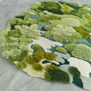 May include: A green, blue, and white rug with a textured, abstract design. The rug is made of soft, fluffy fibers and has a unique, organic look.