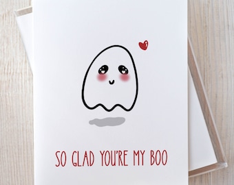 May include: A white card with a cute cartoon ghost with red cheeks and a red heart above it. The text "SO GLAD YOU'RE MY BOO" is written in red below the ghost.