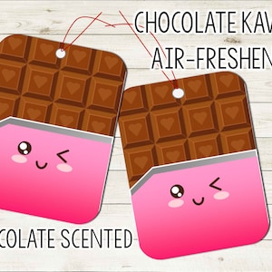 May include: Two pink and brown chocolate bar-shaped air fresheners with cute cartoon faces. The text "CHOCOLATE KAWII AIR-FRESHENER" is at the top of the image and "CHOCOLATE SCENTED" is at the bottom.