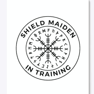 May include: Black and white graphic design of a shield maiden in training. The design features a circle with the text "Shield Maiden in Training" and a compass rose with runes around the outside.