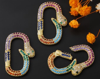 May include: Three gold-toned snake-shaped clasps with colorful rhinestones. Each clasp features a different color scheme of purple, blue, green, orange, and turquoise.