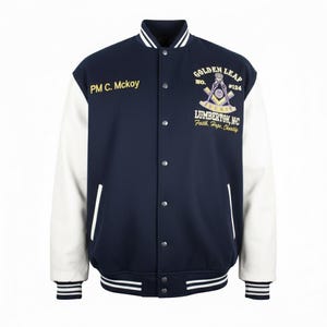 May include: A navy blue and white letterman jacket with the text "PM C. Mckoy" on the chest. The back of the jacket features a Masonic emblem with the words "GOLDEN LEAP" and "LUMBERTON, NC". The jacket has a striped collar, cuffs, and hem.
