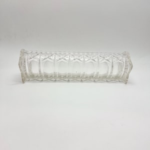 May include: A clear glass rectangular vase with a diamond pattern. The vase is empty and has a slightly rounded shape.