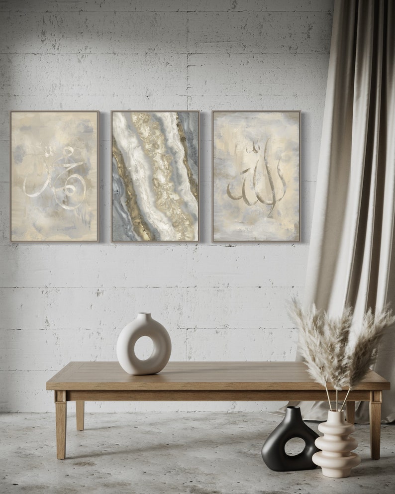 Pu&ograve; includere: Tre dipinti astratti incorniciati con calligrafia araba in oro e bianco su uno sfondo grigio chiaro. I dipinti sono appesi a un muro di mattoni bianchi. Un tavolino da caff&egrave; in legno con un vaso in ceramica bianca e altri due vasi in nero e beige sono in primo piano.