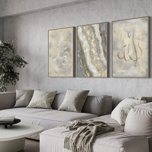 Pu&ograve; includere: Tre stampe d'arte astratta incorniciate in un soggiorno. Le stampe presentano uno schema di colori grigio e oro con calligrafia araba. Le stampe sono appese a una parete grigia sopra un divano angolare grigio.