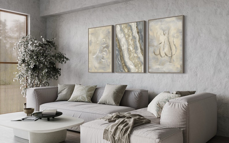 Pu&ograve; includere: Tre stampe d'arte astratta incorniciate in un soggiorno. Le stampe presentano uno schema di colori grigio e oro con calligrafia araba. Le stampe sono appese a una parete grigia sopra un divano angolare grigio.