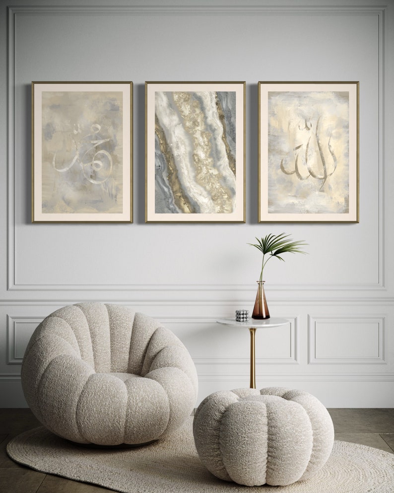 Pu&ograve; includere: Tre stampe d'arte incorniciate con uno sfondo grigio chiaro e calligrafia dorata. Le stampe sono appese a una parete bianca sopra una poltrona e un pouf morbidi bianchi.