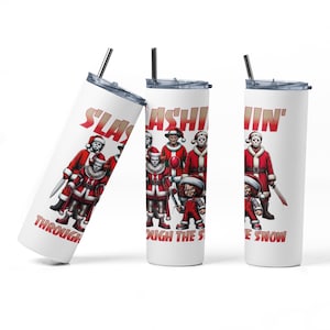 Könnte beinhalten: Ein weißer Edelstahlbecher mit einem weihnachtlichen Design, das verschiedene Horrorfilmfiguren zeigt, die als Weihnachtsmann verkleidet sind. Der Text lautet "Slashi'n Through The Snow".