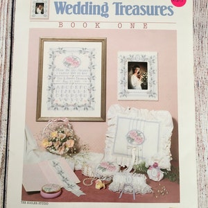 May include: A cross stitch pattern book titled "Wedding Treasures Book One" by Nancy Rossi. The cover features a variety of cross stitch designs, including a wedding bouquet, a pillow, a garter, and a small box. The book is published by Dimensions.