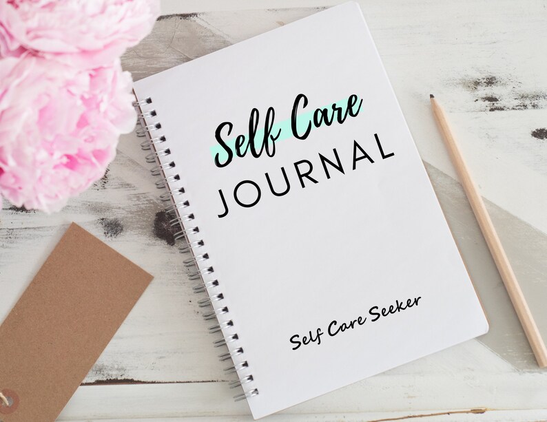 May include: A white spiral bound journal with the text "Self Care JOURNAL" in black lettering. A light blue line is drawn under the word "Self". The text "Self Care Seeker" is printed in black at the bottom of the journal.