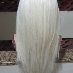 Puede incluir: Una peluca larga, recta, de color rubio platino con un corte recto.