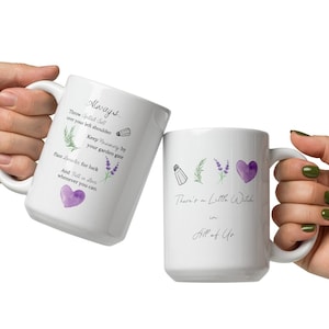 May include: Two white ceramic mugs with purple and green floral designs. The mug on the left has the text "Always There Should Be" and the mug on the right has the text "There's a Little Witch in All of Us".