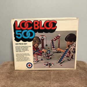 May include: A box for a 500 piece Loc Bloc construction toy set. The box shows two children playing with the blocks. The box is white with red, blue, and white accents. The text on the box reads "Loc Bloc 500 500 Piece Set Lots of construction blocks of various shapes, sizes and colors for boys and girls 5-12."