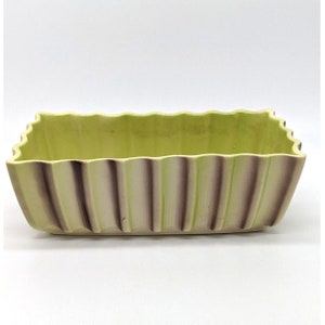 May include: A rectangular ceramic planter with a light green glaze and brown vertical stripes. The planter has a wavy rim.