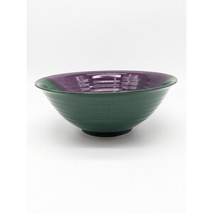 May include: A green and purple ceramic bowl with a rounded shape. The bowl has a glossy finish and is perfect for serving soup, salad, or other dishes.