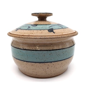 May include: A brown ceramic casserole dish with a lid. The dish has a blue and black design around the top and a blue stripe around the middle.