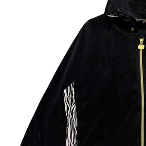 May include: Black hooded jacket with a zipper closure and a zebra print detail on the sleeve.