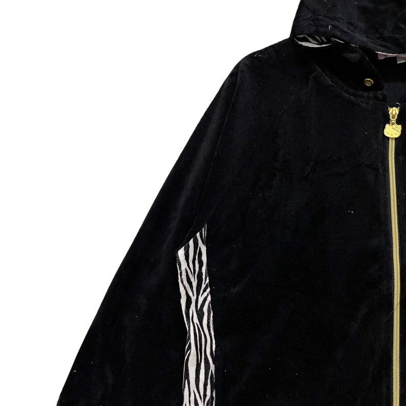 May include: Black hooded jacket with a zipper closure and a zebra print detail on the sleeve.