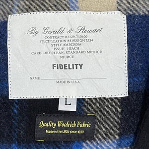 May include: A white rectangular garment label with black text reading By Gerald & Stewart, Contract #2129-710100, Specification #81035-2917534, Style #M3020364, Issue: 1 Each, Care: Dry Clean, Standard Method, Fidelity, Name, and Made in U.S.A.