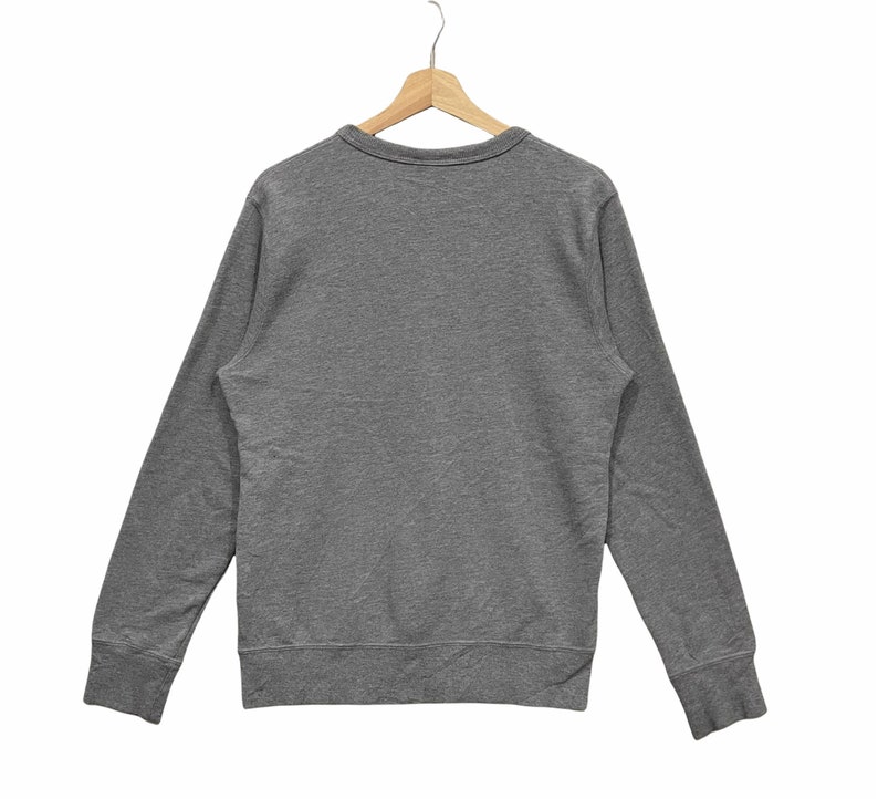 May include: A heather gray long-sleeve sweatshirt with a crew neck, displayed on a wooden hanger. The sweatshirt has ribbed cuffs and hem. The fabric appears to be a soft, comfortable material.