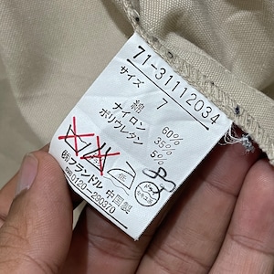 May include: Close-up of a clothing tag with Japanese text and numbers. The tag displays fabric composition percentages: 60% cotton, 35% nylon, and 5% polyurethane. Washing instructions are also visible.