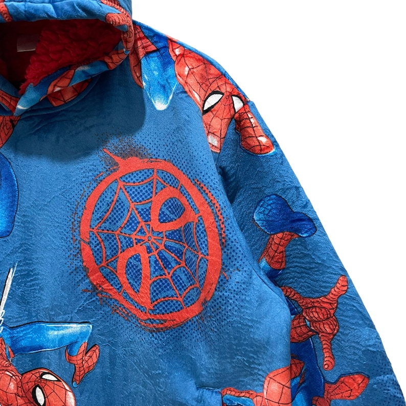 Puede incluir: Manta con capucha azul con gr&aacute;ficos de Spider-Man. La manta presenta un dise&ntilde;o de telara&ntilde;a roja y m&uacute;ltiples im&aacute;genes de Spider-Man. La capucha est&aacute; forrada con tela roja. La manta est&aacute; hecha de un material suave y texturizado.