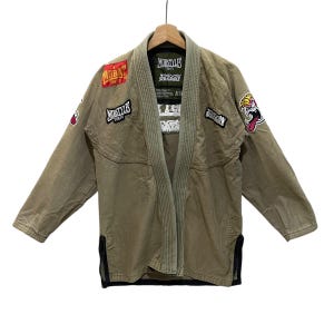 May include: A green martial arts gi with several patches, including "Morstyles Tokyo" and "Mobat", and a cartoon character with a red tongue.