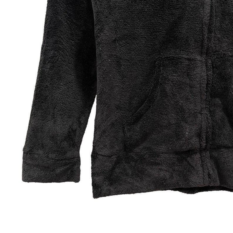 Peut inclure: Une veste en polaire noire avec une fermeture &eacute;clair et une poche sur le devant.