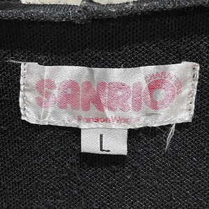 May include: A close-up of a black garment tag with the word "SANDRO" in pink letters. The tag also features a pink crown design and the size "L" in a white rectangle.