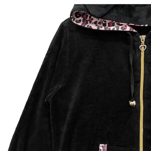 Pode incluir: Camisola de veludo preto com capuz, z&iacute;per dourado e forro de leopardo rosa e marrom no capuz.