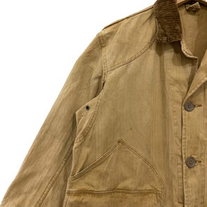 May include: A brown corduroy-collared jacket with a button-up front and two large pockets. The jacket is made of a thick, durable fabric and has a vintage look.