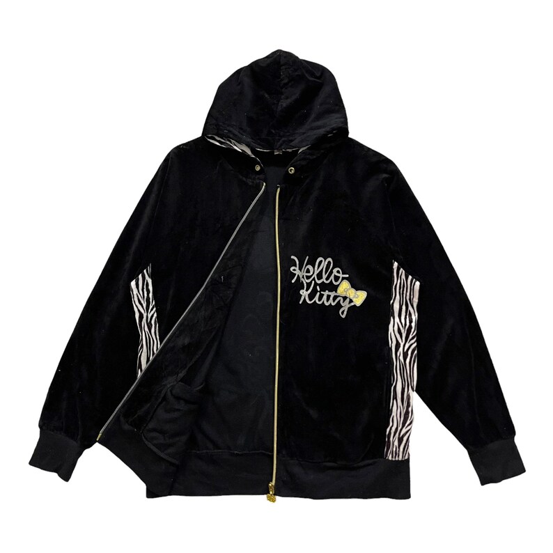 May include: Black velour zip-up hoodie with a Hello Kitty design featuring a yellow bow. The hoodie has a zebra print on the sleeves and a black lining.