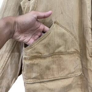 May include: A tan utility jacket with a large, angled pocket on the front. The pocket has a flap and a button closure.