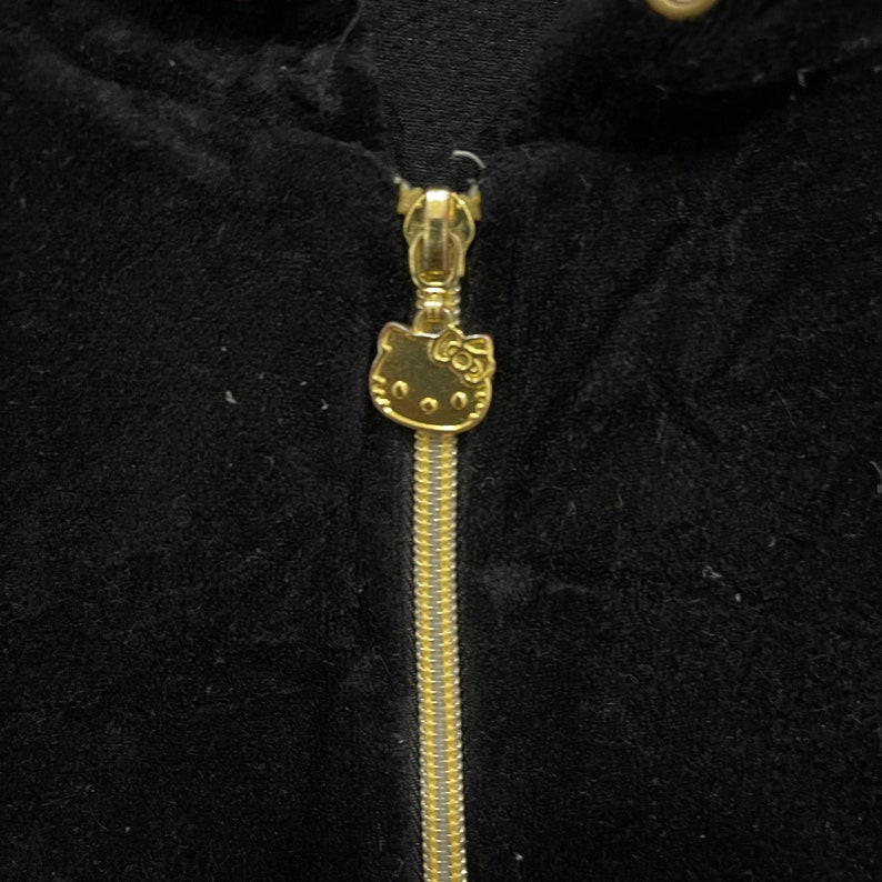 May include: A black velvet jacket with a gold zipper and a Hello Kitty charm.
